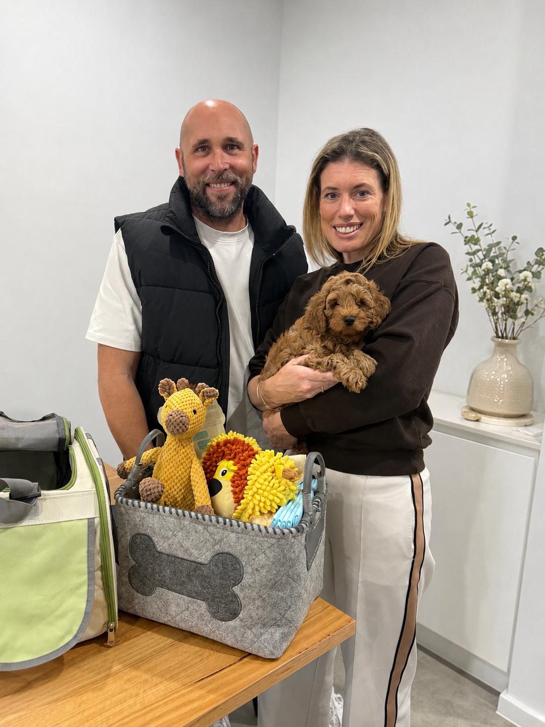 A family with their new Cavoodle puppy and puppy pack